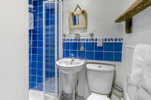 ein blau-weißes Bad mit einem WC und einem Waschbecken in der Unterkunft Smugglers Cottage in Porthleven