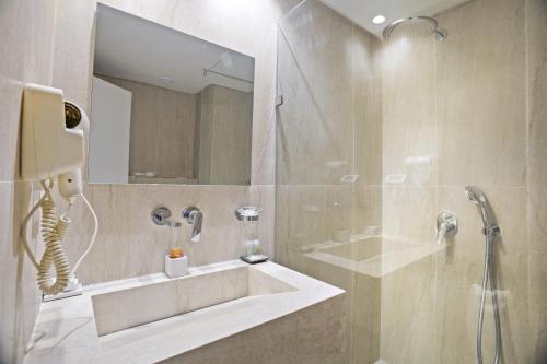a bathroom with a tub and a shower with a mirror at Hotel Donia Sfax in Sfax