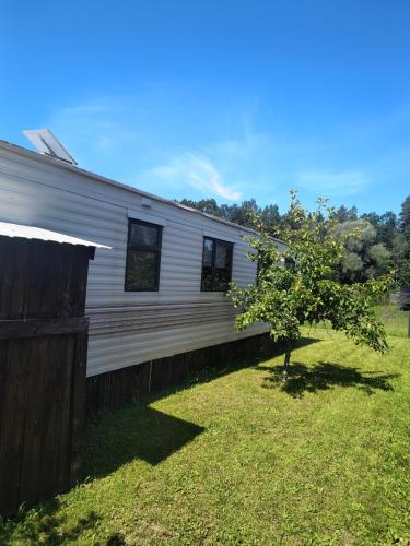 a white house with a tree in the yard at Leśna Aura in Ponizie