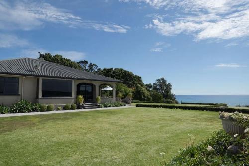 a house with a large yard with the ocean in the background at Bungalow Coastal Retreat - large luxury homestead in Tataraimaka