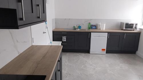 a kitchen with black cabinets and a white refrigerator at 4 Ensuite Bedroom Dublin Airport Free Parking in Dublin