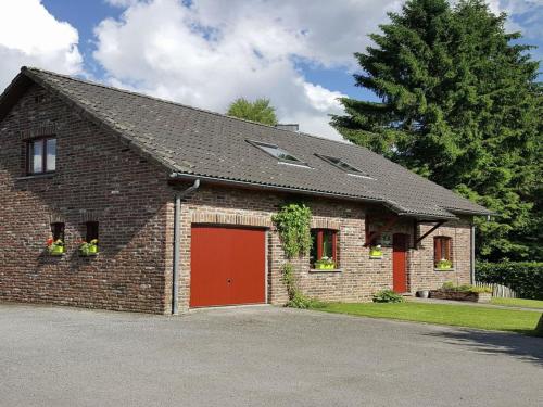 une maison en briques avec un garage rouge dans l'établissement Waimes Forest-Edge Escape, à Sourbrodt