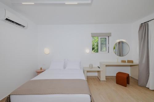 a white bedroom with a bed and a desk at Pension Zoi Luxury Room in Kolymbia