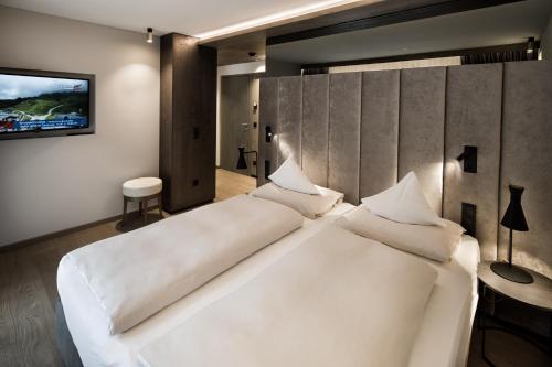a large white bed in a room with a tv at Brugger's Genießerhotel Lanersbacherhof in Tux