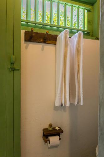 a bathroom with white towels and a toilet paper roll at Casa Mangará in Cruz