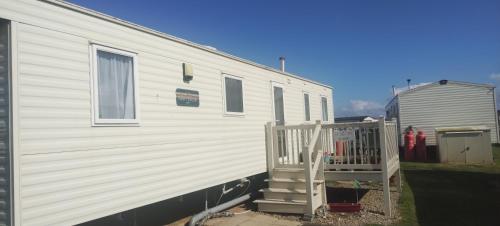 a white trailer with a staircase next to a house at Beach Haven at Berwick in Berwick-Upon-Tweed