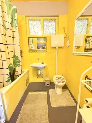 a yellow bathroom with a toilet and a sink at Small house at seafront in Tisno