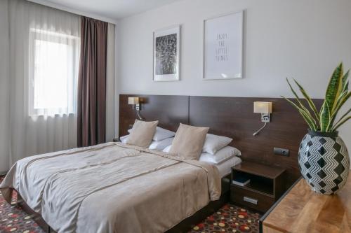 a bedroom with a large bed and a vase at Budapest Airport Hotel Stáció Wellness & Konferencia in Vecsés