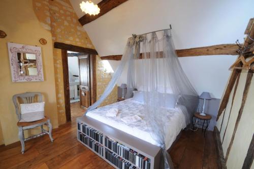 Saint-Germain-des-GroisにあるAu bord de l'Huisneのベッドルーム(天蓋付きベッド1台、椅子付)