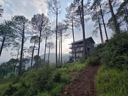 a house on the side of a hill with a dirt road at Lè Nest Residences in Murree