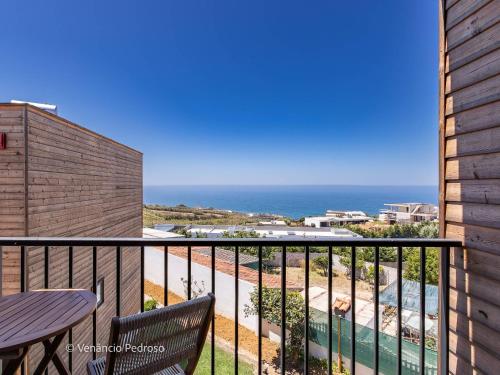 a balcony with a table and chairs and the ocean at Ericeira Coxos Beach Lodge in Santo Isidoro