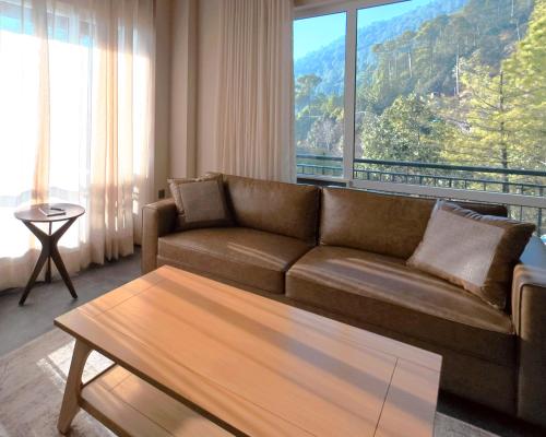 Una sala de estar con un sofá y una ventana grande. en Lè Nest Residences, en Murree