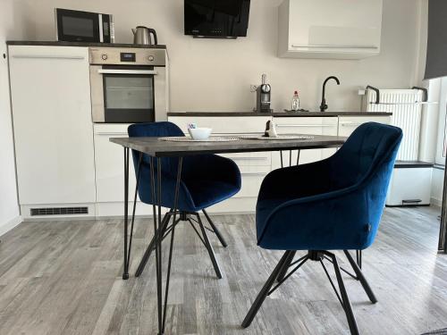 a kitchen with a table and two blue chairs at Casa Wimmer in Allendorf an der Lumda