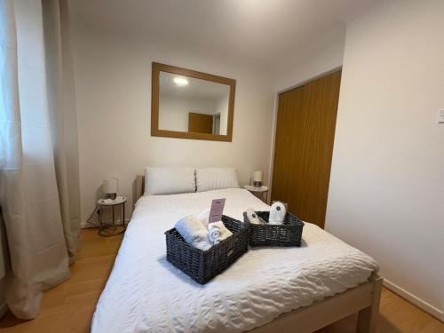 a bedroom with a bed with two baskets on it at Misk Homes #3 Near Heathrow Airport, shops & Brunel University - Free Parking in Uxbridge