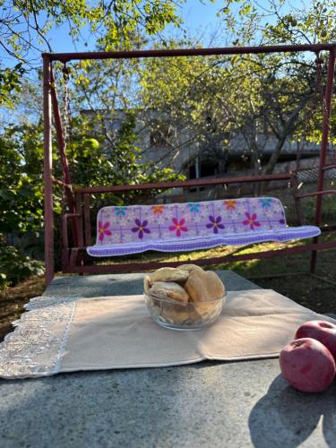 eine Schüssel Brot auf einem Tisch neben einer Bank in der Unterkunft Chelo Guest House in Kutaissi