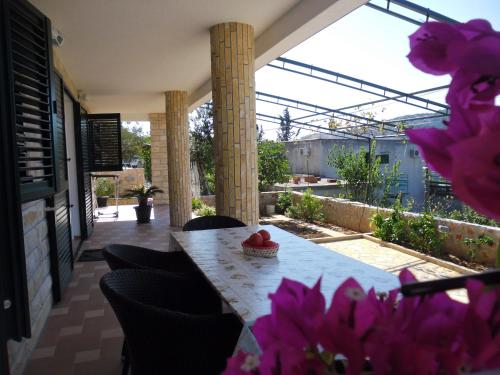 a table and chairs on a patio with pink flowers at Apartments Hari Tisno in Tisno