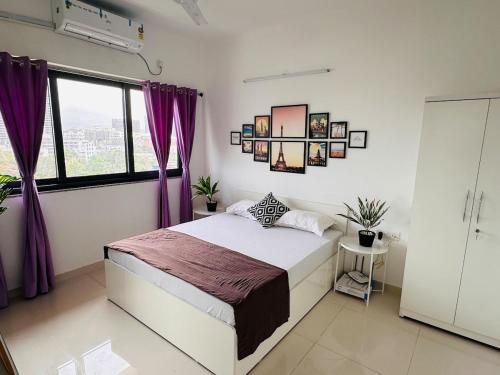 a bedroom with a large bed with purple curtains at Joy Pvt 1Bhk in Amanora Most Awarded Township in Pune