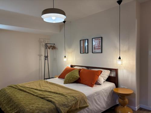a bedroom with a bed with orange and green pillows at Cozy Loft tout équipé au cœur de Saint-Lô in Saint Lo