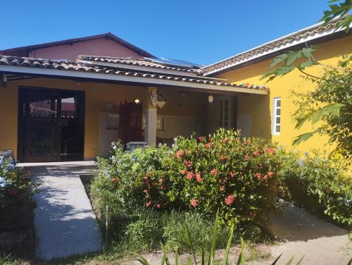 a yellow house with flowers in front of it at Lumiar Garden Suítes e Chalés em Vilas do Atlântico in Lauro de Freitas