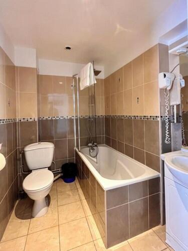 a bathroom with a toilet and a tub and a sink at Luxor Bastille Hotel in Paris