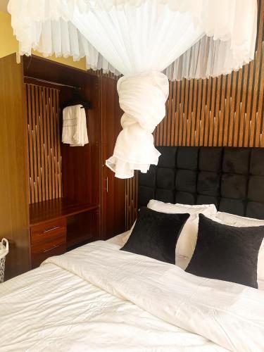 a bedroom with a bed with white sheets and a chandelier at Home Haven - 1 Bedroom Apartment in Kisumu