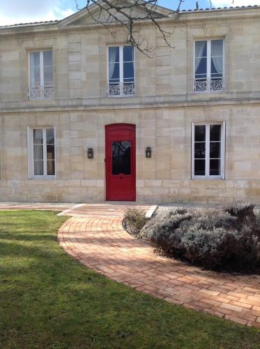 Un edificio de piedra con una puerta roja y un patio. en Château Ormes de Pez, en Saint-Estèphe