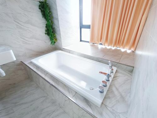 a white bath tub in a bathroom with a window at Imperio Residence Melaka by Jeffery Lam Home Management in Melaka
