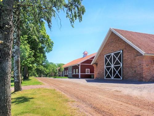 a red barn with a dirt road next to it at 14 person holiday home in HOVA-By Traum in Hova