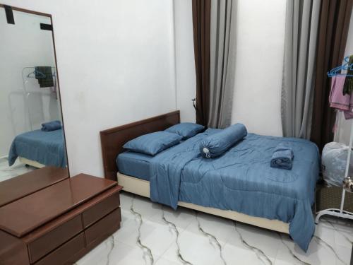 a bedroom with a bed with blue sheets and a mirror at Seri Desa Homestay in Kuala Terengganu