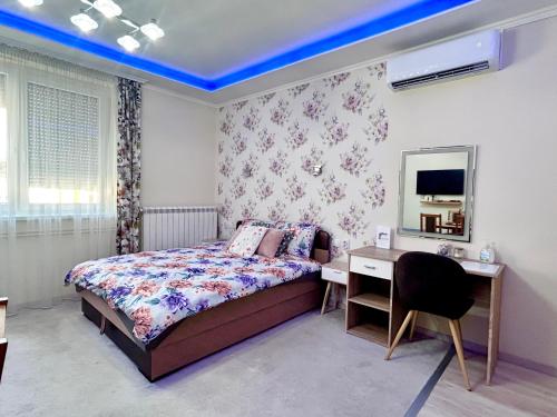 a bedroom with a bed and a desk and a mirror at Belien Apartman in Makó