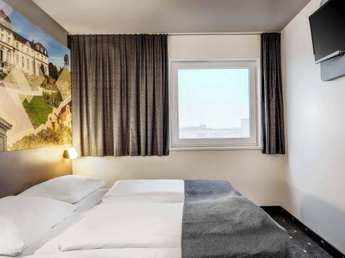 two beds in a hotel room with a window at B&B Hotel Bonn-West in Bonn