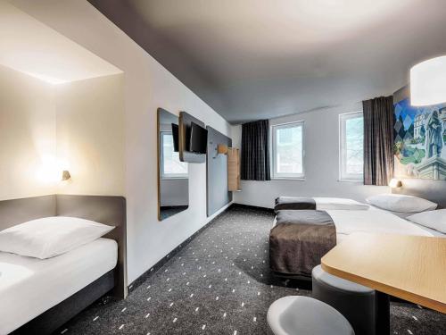 a hotel room with two beds and a table at B&B Hotel Bonn-West in Bonn