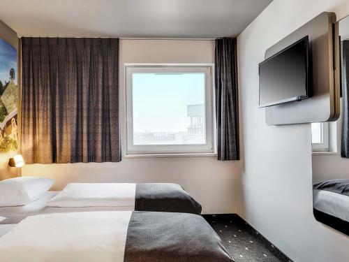 a hotel room with a bed and a flat screen tv at B&B Hotel Bonn-West in Bonn