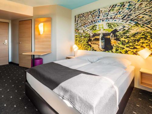a hotel room with a bed with a painting on the wall at B&B Hotel Karlsruhe in Karlsruhe