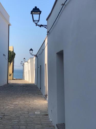 a street with white buildings and the ocean in the background at Casa Vacanze Sos Vrades in Portoscuso