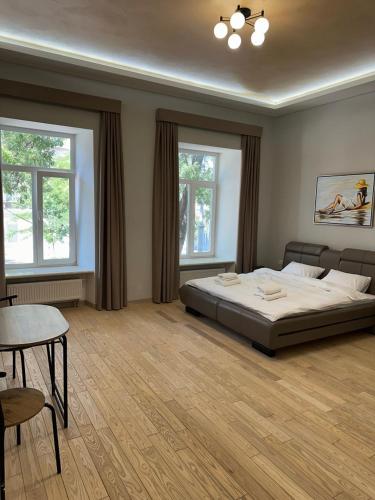a bedroom with a bed and a table and two windows at Отель Преображенский in Odesa