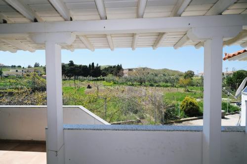 a white porch with a view of a garden at Convenient Apartment in Limnos Near Port in Mirina
