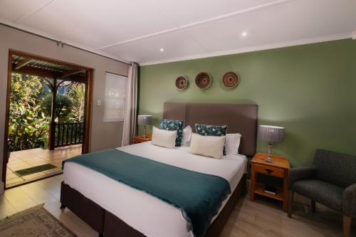 a bedroom with a large bed and a chair at 88 Baron van Reede Guesthouse in Oudtshoorn