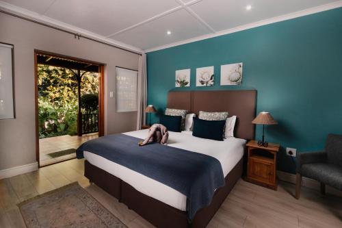 a bedroom with a large bed with a person laying on it at 88 Baron van Reede Guesthouse in Oudtshoorn