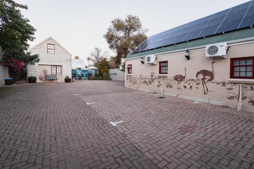 a brick parking lot with ostriches painted on the side of a building at 88 Baron van Reede Guesthouse in Oudtshoorn