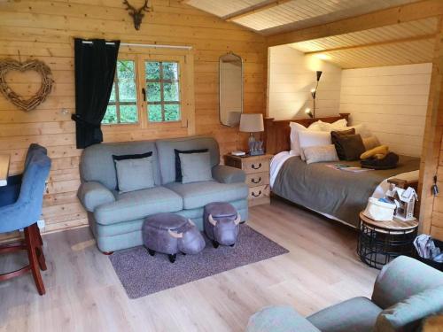 a living room with a couch and a bed in a cabin at 1-Bed Cabin 2 adults Wood Burning Hot Tub & Fire in Carluke