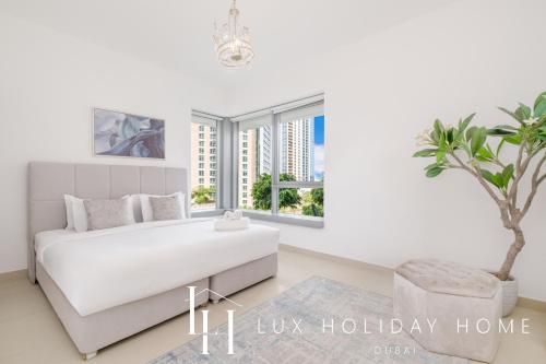 a white bedroom with a large bed and a palm tree at LUX - The Downtown Blvd Suite in Dubai