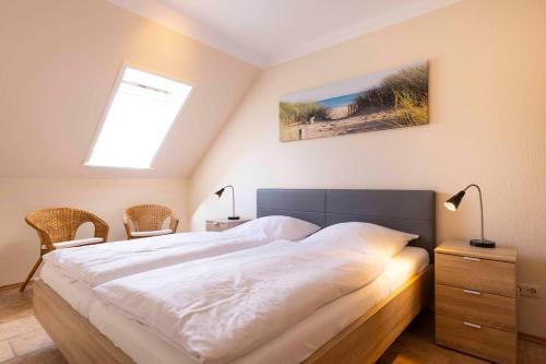 a bedroom with a bed and two chairs and a window at MEI27a Ferienwohnung Ostseetraum in Niendorf