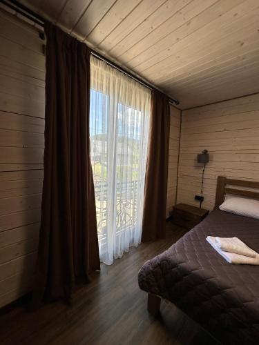 a bedroom with a bed and a large window at Біля Плаю in Plav'ya