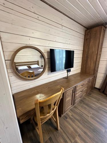 a room with a television and a mirror and a chair at Біля Плаю in Plav'ya