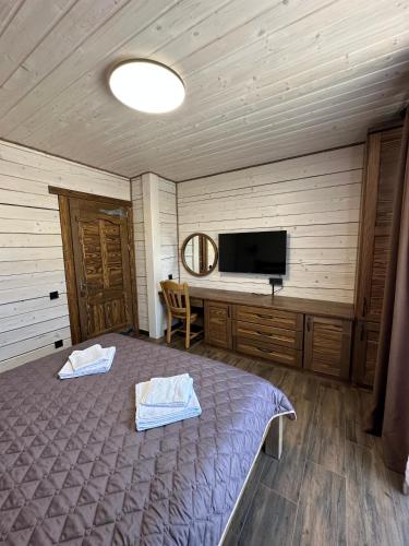 a bedroom with a bed and a flat screen tv at Біля Плаю in Plav'ya
