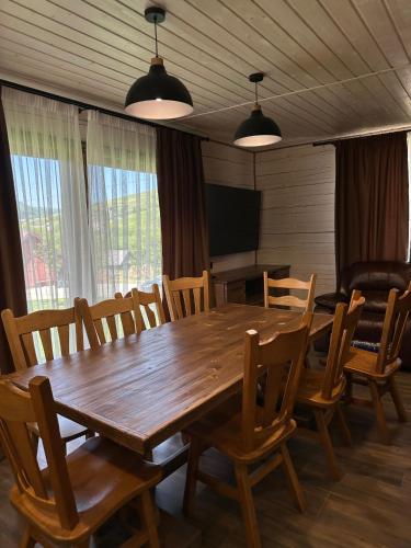a dining room with a wooden table and chairs at Біля Плаю in Plav'ya