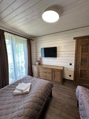 a bedroom with a bed and a flat screen tv at Біля Плаю in Plav'ya