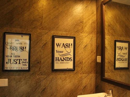 a bathroom with three framed signs on a wall at Seeya Heritage Hostels in North goa