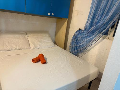 a orange stuffed animal sitting on a white bed at La Stanza del Mare in Calasetta